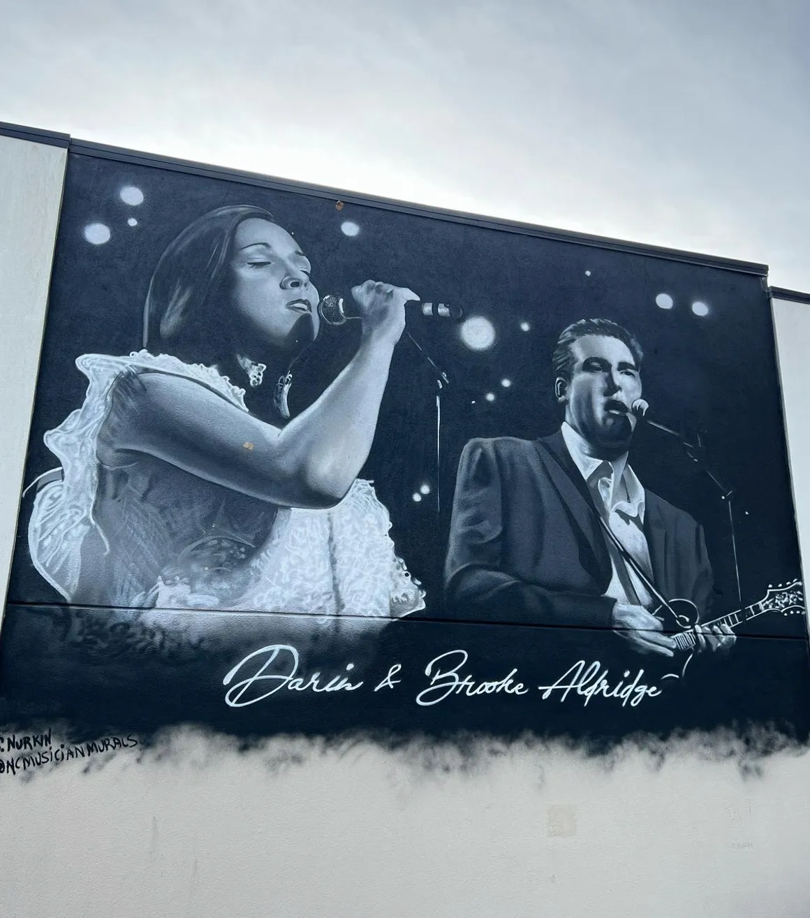 A large black and white photo of two people singing