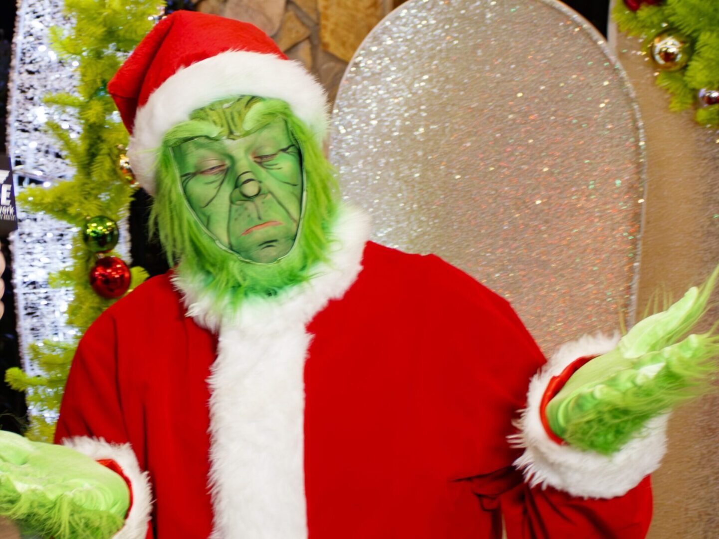 A man dressed up as the grinch in a red santa suit with green face paint. 