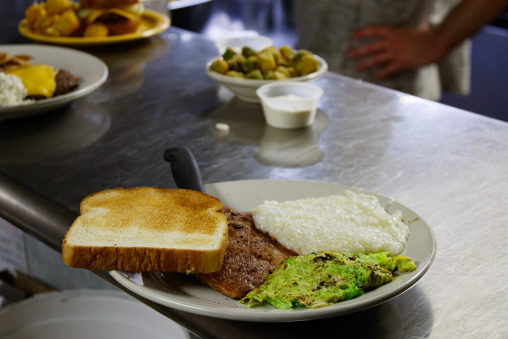 A plate of food featuring toast, country ham, grits, and green eggs. 