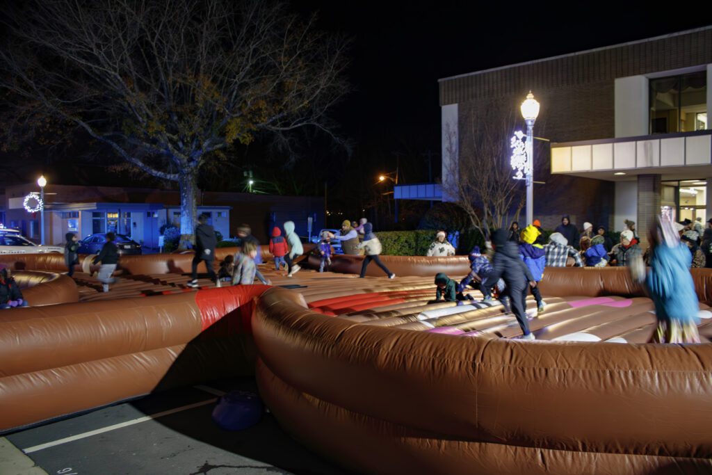 Children jumping on a giant brown inflatable meant to look like a gingerbread man. 