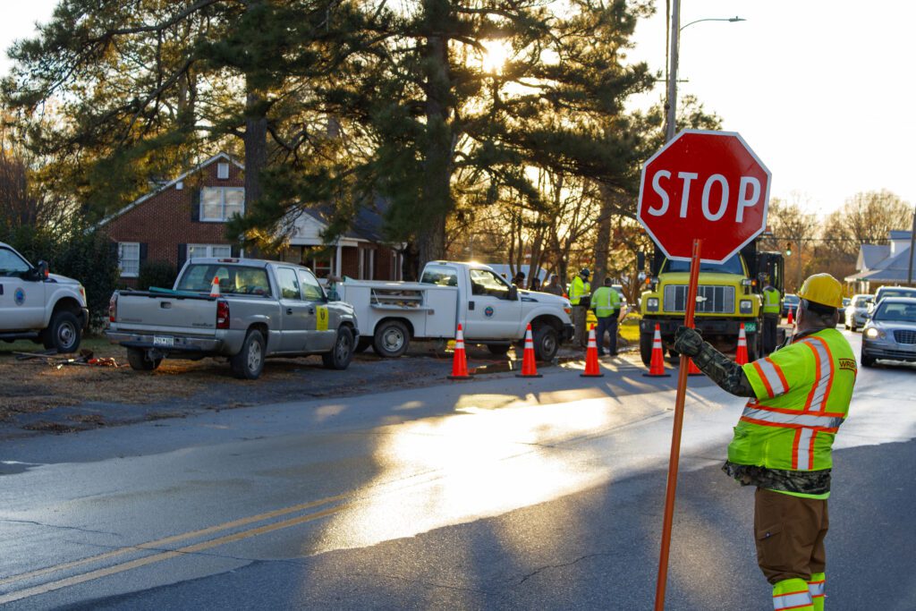 A man in a yellow construction vest holding a stop sign at a traffic stop.