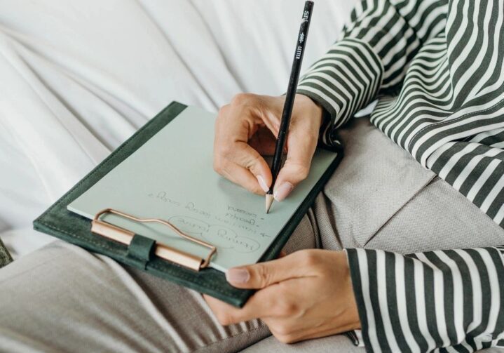 A stock photo of a woman writing on a notepad.