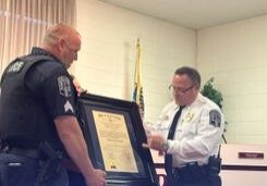 A police officer is handing over the certificate to another cop.